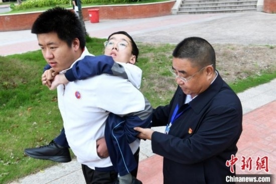 朱金祥背著鐘華強去教室上課的路上，也經(jīng)常碰到值班的校領(lǐng)導(dǎo)和老師前來搭把手。 卓忠偉 攝