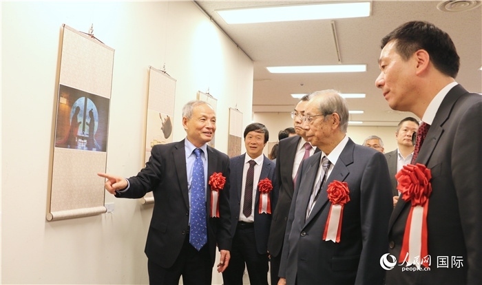 “湖州印象”攝影展主創(chuàng)、世界華人攝影協(xié)會(huì)副會(huì)長(zhǎng)馮學(xué)敏向吳江浩大使、福田康夫前首相等嘉賓介紹展出作品。（人民網(wǎng) 許可攝）