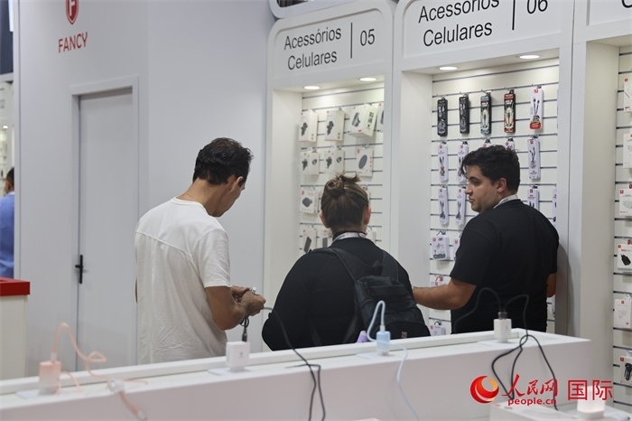 幾名參觀者在一個展臺前了解手機配件。（人民網記者 時元皓攝）