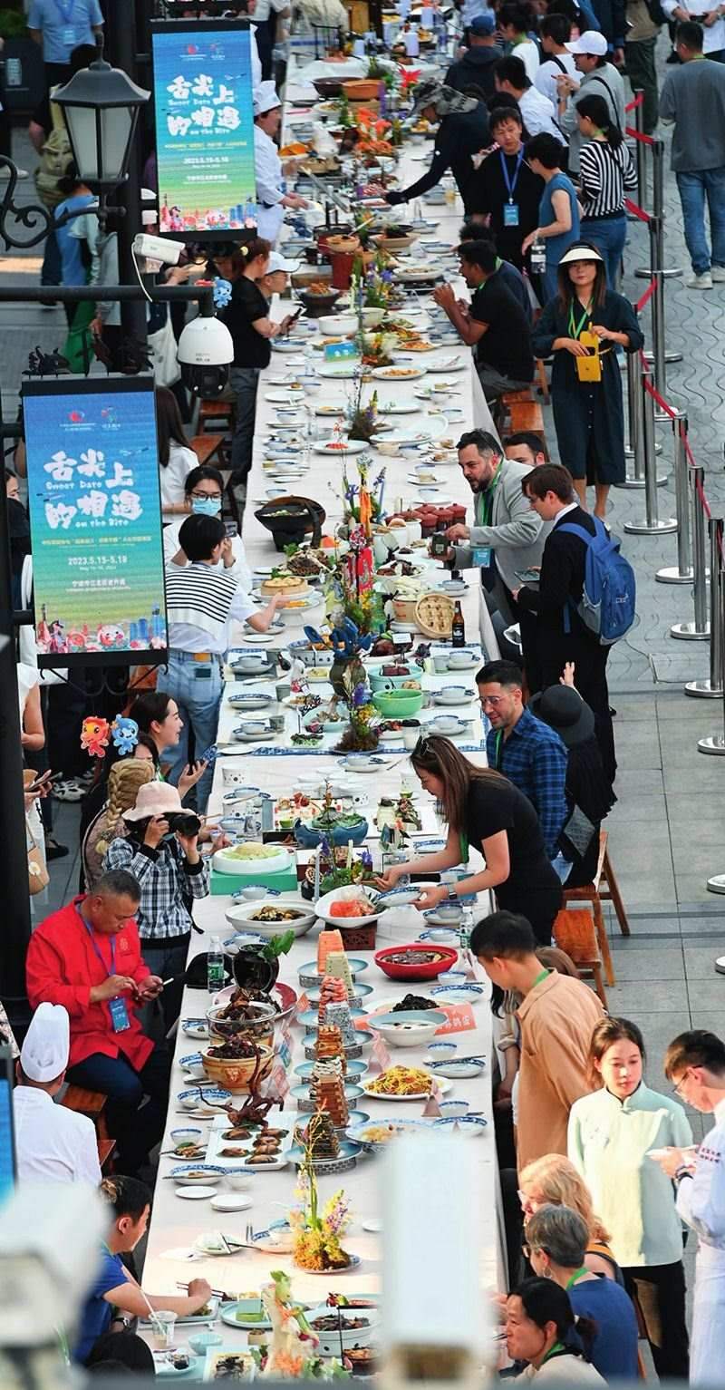 市民和游客在寧波舉辦的第三屆中國(guó)—中東歐國(guó)家博覽會(huì)暨國(guó)際消費(fèi)品博覽會(huì)上品嘗融合中國(guó)和中東歐美食的長(zhǎng)桌宴（2023年5月15日攝）。黃宗治攝/本刊