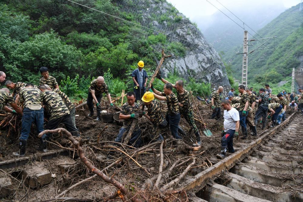 8月1日，在北京市門頭溝區(qū)水峪嘴村附近一段被阻斷的鐵路線上，中鐵六局工作人員在清理軌道上的雜物，全力恢復交通。新華社記者 鞠煥宗 攝