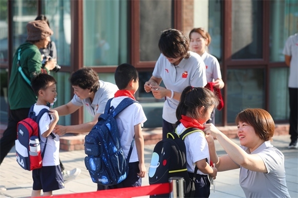 8月30日，雄安史家胡同小學學生體驗學校生活。老師為學生佩戴校徽。