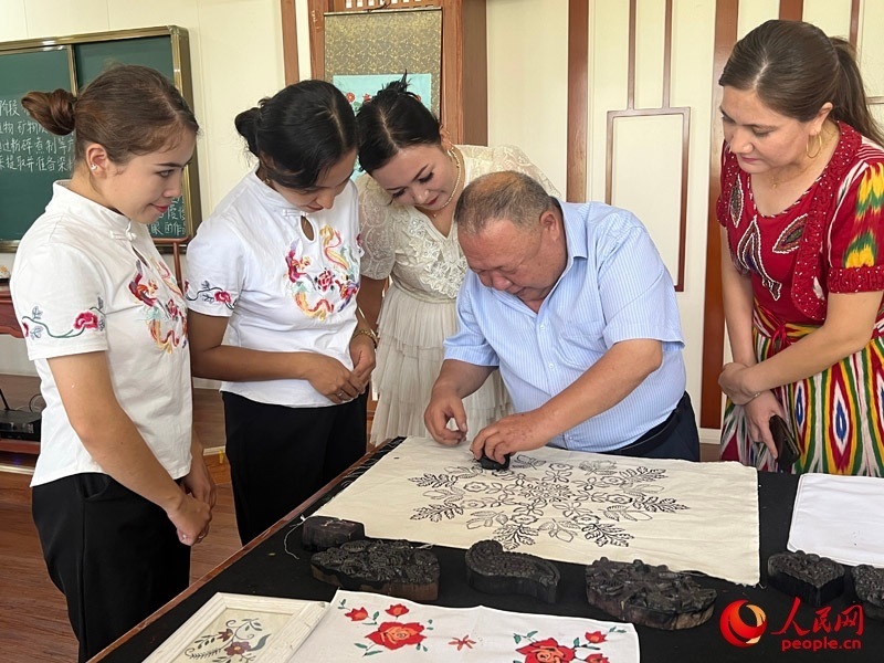 國(guó)家級(jí)非物質(zhì)文化遺產(chǎn)模戳印花布技藝傳承人吾吉阿西木?吾舒爾展示模戳印花布的制作過(guò)程。人民網(wǎng)記者 常雪梅攝