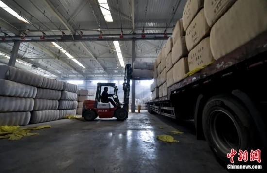 新疆喀什綜合保稅區(qū)，喀什啟路國(guó)際貿(mào)易有限公司的倉(cāng)庫(kù)內(nèi)，工人正在裝載從塔吉克斯坦和烏茲別克斯坦進(jìn)口的棉花。劉新攝