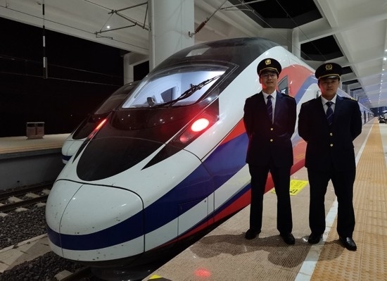 劉銀能（右一）與中國師父鄔俊鴻在動車組前合影。受訪者供圖