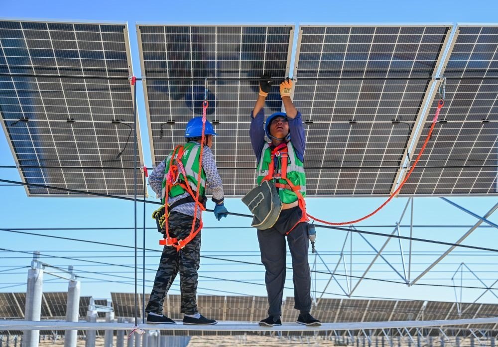 2023年7月22日，工人在位于內(nèi)蒙古杭錦旗庫布其沙漠億利生態(tài)示范區(qū)的蒙西基地庫布其200萬千瓦光伏治沙項目工地安裝光伏板。新華社記者 劉磊 攝