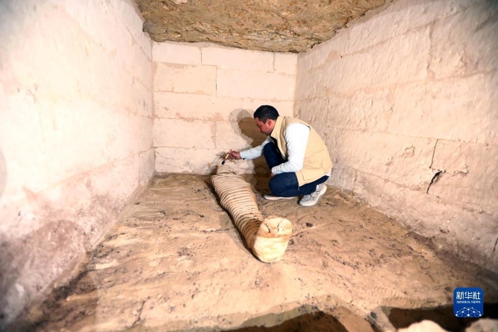 10月15日，在埃及明亞省考古現(xiàn)場，考古人員清理一座石鑿墓中的木乃伊。新華社發(fā)（艾哈邁德·戈馬攝）