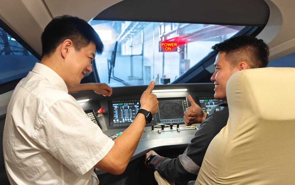 8月25日，在印度尼西亞萬(wàn)隆的雅萬(wàn)高鐵德卡魯爾動(dòng)車所內(nèi)，中國(guó)師傅穆振（左）在向印尼火車司機(jī)塞蒂亞萬(wàn)講解動(dòng)車組出庫(kù)前的上電作業(yè)。