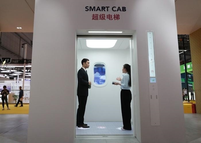 11月5日，工作人員（右）在第六屆進(jìn)博會上向參觀者介紹奧的斯公司全新推出的超級電梯。