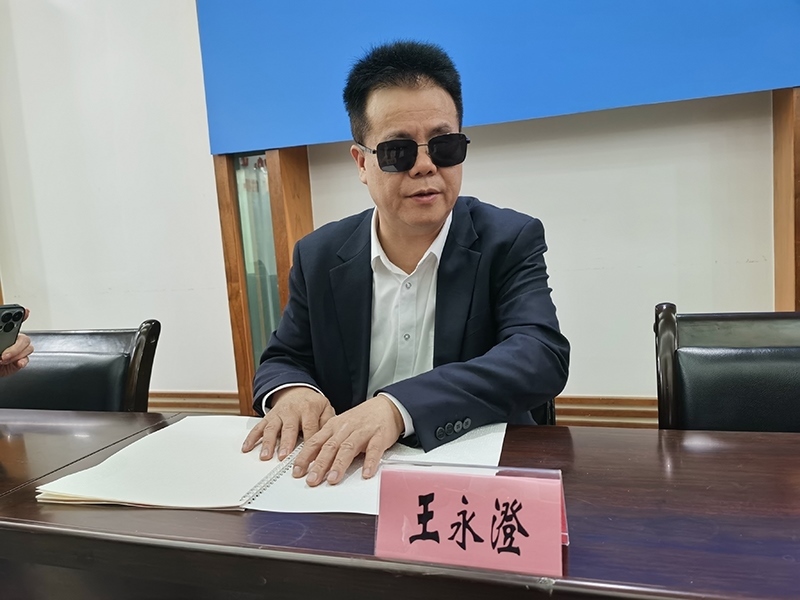 全國(guó)人大代表王永澄正在閱讀盲文版代表建議答復(fù)。本報(bào)記者 張 璁?dāng)z