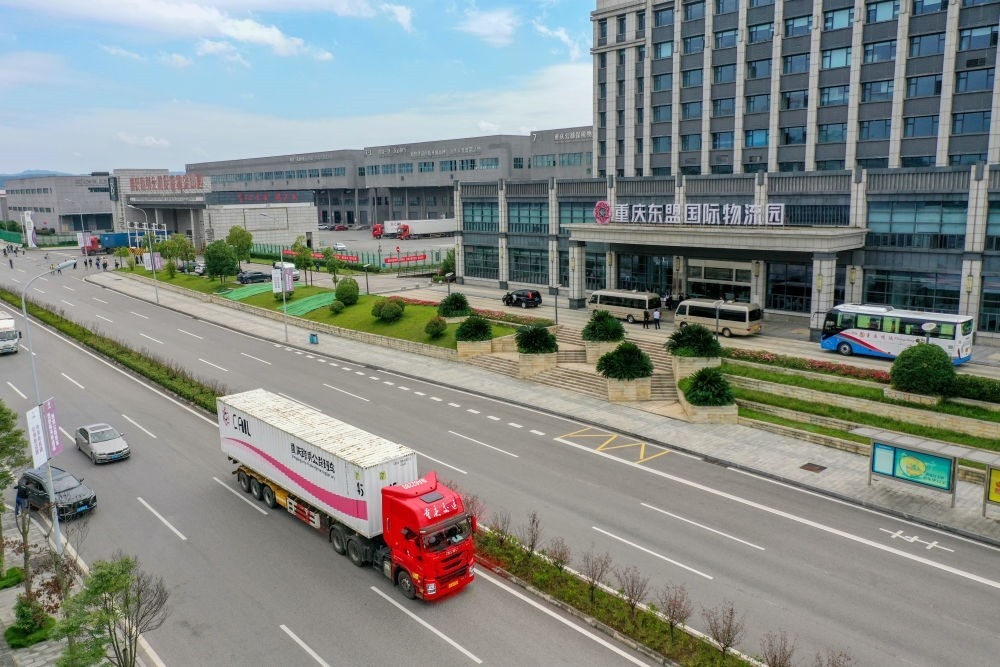 2023年10月11日，滿載筆記本電腦配件、發(fā)電機組件等產(chǎn)品的西部陸海新通道跨境公路班車從重慶南彭公路保稅物流中心駛出，將途經(jīng)廣西憑祥，直達越南（無人機照片）。新華社記者 黃偉 攝