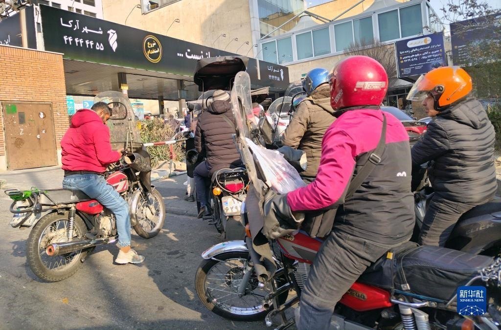 12月18日，摩托車(chē)在伊朗首都德黑蘭的一家加油站外等待加油。新華社記者 沙達(dá)提 攝