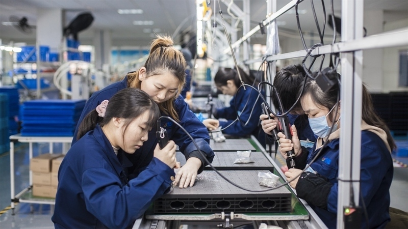 在新亞勝光電的產(chǎn)品線上，工人正進行產(chǎn)品組建和安裝布線。受訪者供圖