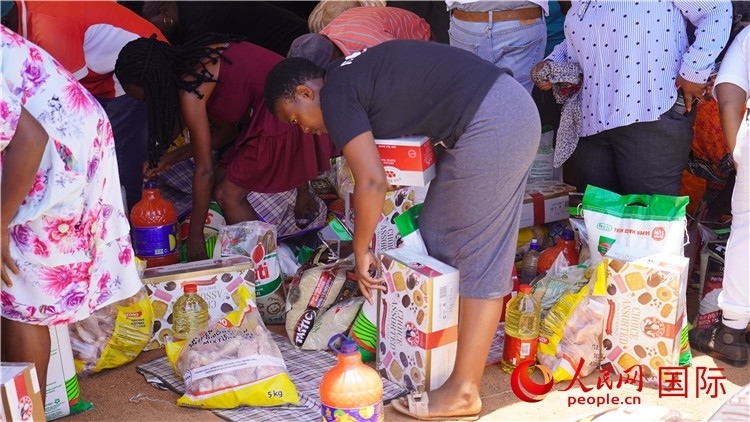 當(dāng)?shù)厣鐓^(qū)家庭領(lǐng)取物資。人民網(wǎng) 張茜攝