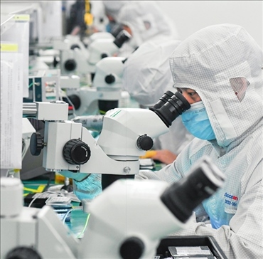 在位于武漢中國(guó)光谷的光電器件研發(fā)制造商——武漢光迅科技股份有限公司生產(chǎn)車(chē)間內(nèi)，技術(shù)人員在光模塊生產(chǎn)線作業(yè)（2023年4月11日攝）。程敏攝/本刊