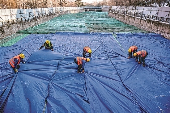 1月3日，房山區(qū)東風(fēng)街道，工人正在修復(fù)的河道內(nèi)給混凝土鋪設(shè)保溫布。