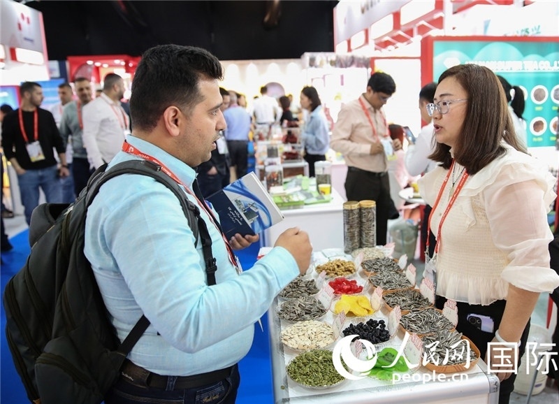 圖為一家中國(guó)干果參展企業(yè)代表與采購(gòu)商洽談。人民網(wǎng) 塔里克·易卜拉欣攝