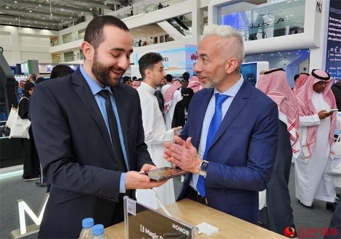 兩名觀眾在榮耀手機展臺前交流。人民網(wǎng)記者 管克江攝