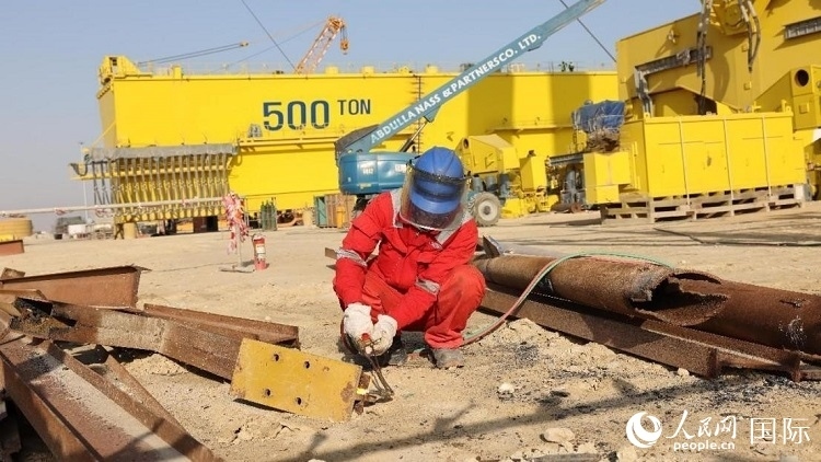 工人正在龍門吊吊裝現(xiàn)場切割金屬件。人民網(wǎng)記者管克江攝