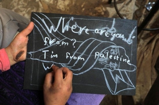 2023年12月28日，一名學(xué)生在加沙地帶南部城市拉法一所學(xué)校的臨時(shí)教室中寫下“我來(lái)自巴勒斯坦”的字樣。新華社發(fā)（里澤克·阿卜杜勒賈瓦德攝）