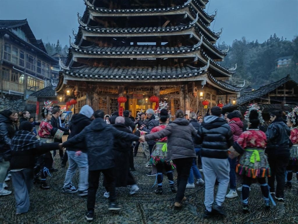 法國青年與當(dāng)?shù)卮迕駹渴痔?。新華社記者 羅羽 攝