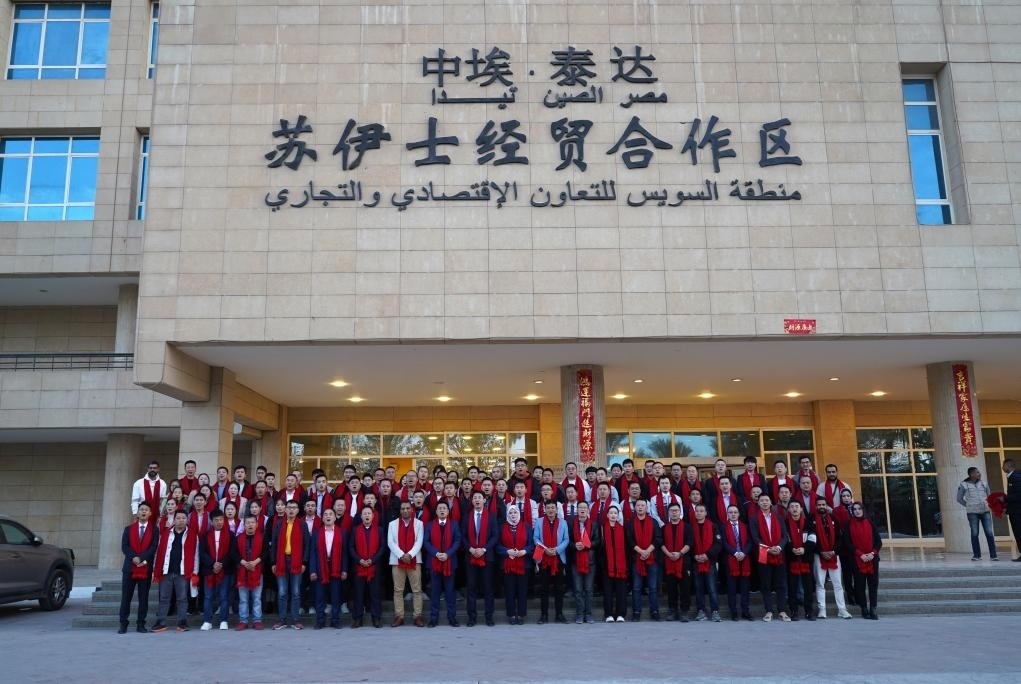 2024年2月11日，在位于埃及蘇伊士省的中?！ぬ┻_(dá)蘇伊士經(jīng)貿(mào)合作區(qū)，中埃員工在合作區(qū)辦公大樓前合影拜年。新華社發(fā)（泰達(dá)合作區(qū)供圖）