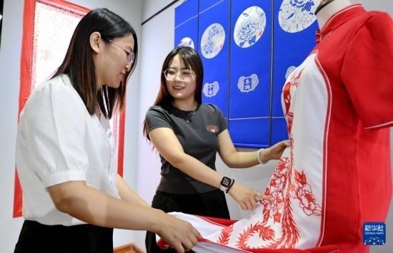 5月31日，在衡水市阜城縣一家剪紙工作室，游客在觀賞帶有剪紙元素的旗袍。