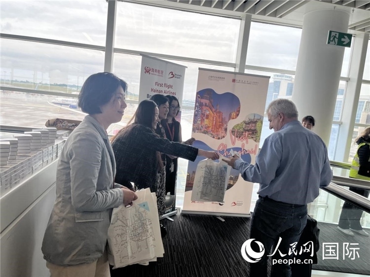 圖為工作人員向乘客發(fā)放復(fù)航首班禮物。 牛瑞飛攝