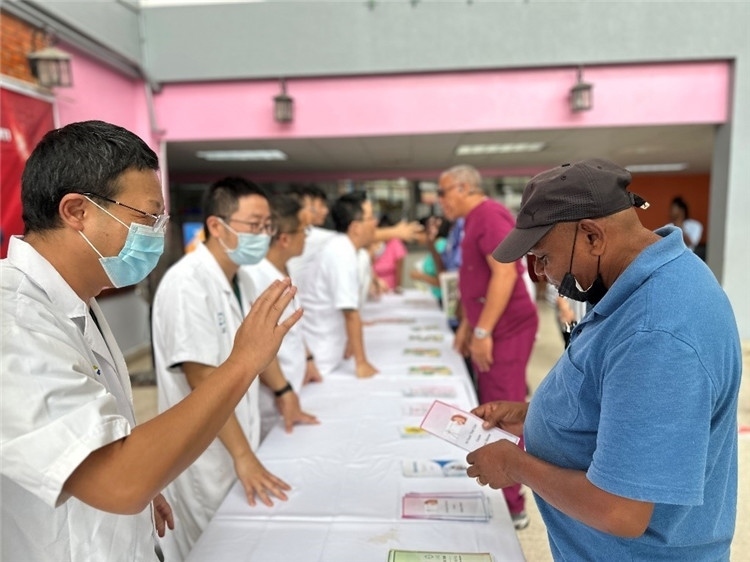 援圭醫(yī)療隊(duì)隊(duì)員們?cè)趩?dòng)儀式上為當(dāng)?shù)孛癖姺职l(fā)宣傳手冊(cè)。中國(guó)援助圭亞那醫(yī)療隊(duì)供圖