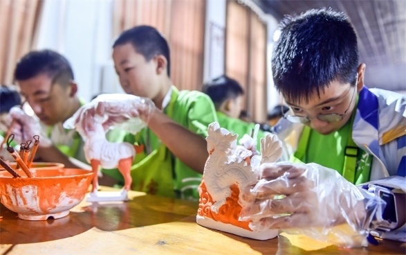 小朋友們?cè)诼尻?yáng)市孟津區(qū)朝陽(yáng)鎮(zhèn)南石山村體驗(yàn)唐三彩素胎施釉技藝。圖片來(lái)源：視覺中國(guó)