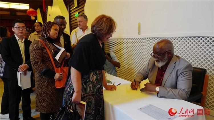 譚哲理在活動(dòng)現(xiàn)場(chǎng)簽名贈(zèng)書。人民網(wǎng) 劉暢攝