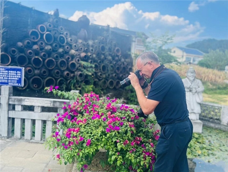 遠處黔北民居錯落有致，近處一只黑色的蝴蝶穿梭于粉紫色三角梅花叢間隙，與俄羅斯“大歐亞”總編輯弗拉基米爾·別列日內赫的鏡頭玩起了捉迷藏，“你追我逃，不亦樂乎”。（張亞欣攝）