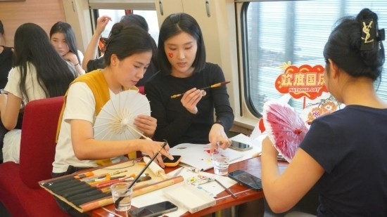10月1日，旅客們在G1634次列車上給油紙傘作畫。新華社記者周義 攝