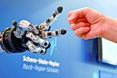 在德國漢諾威工博會上，參觀者與一款智能機(jī)器人進(jìn)行“石頭剪子布”游戲。新華社發(fā)