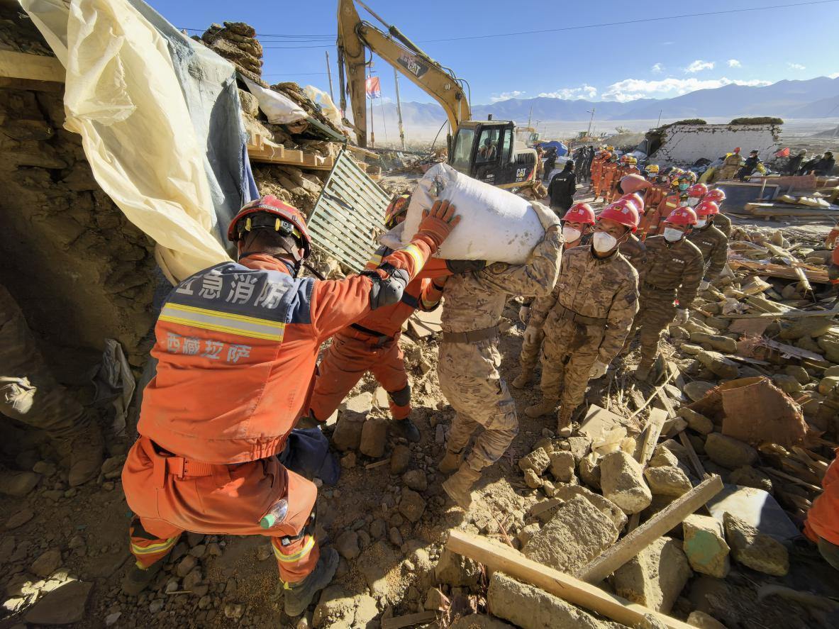 1月11日，定日縣長(zhǎng)所鄉(xiāng)古榮村，應(yīng)急消防等救援人員排隊(duì)接力搶運(yùn)掩埋在倒塌房屋下的群眾財(cái)物。人民日?qǐng)?bào)記者楊翹楚攝