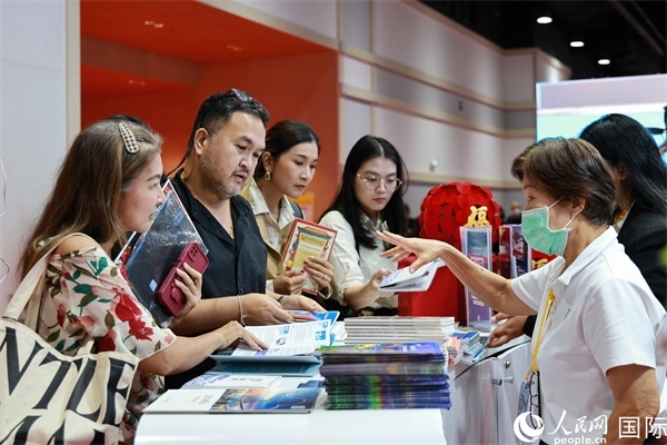 外國觀眾在中國展臺仔細(xì)閱讀赴華旅游介紹，向工作人員咨詢關(guān)于中國美食和景點的詳細(xì)信息。人民網(wǎng)記者 白元琪攝