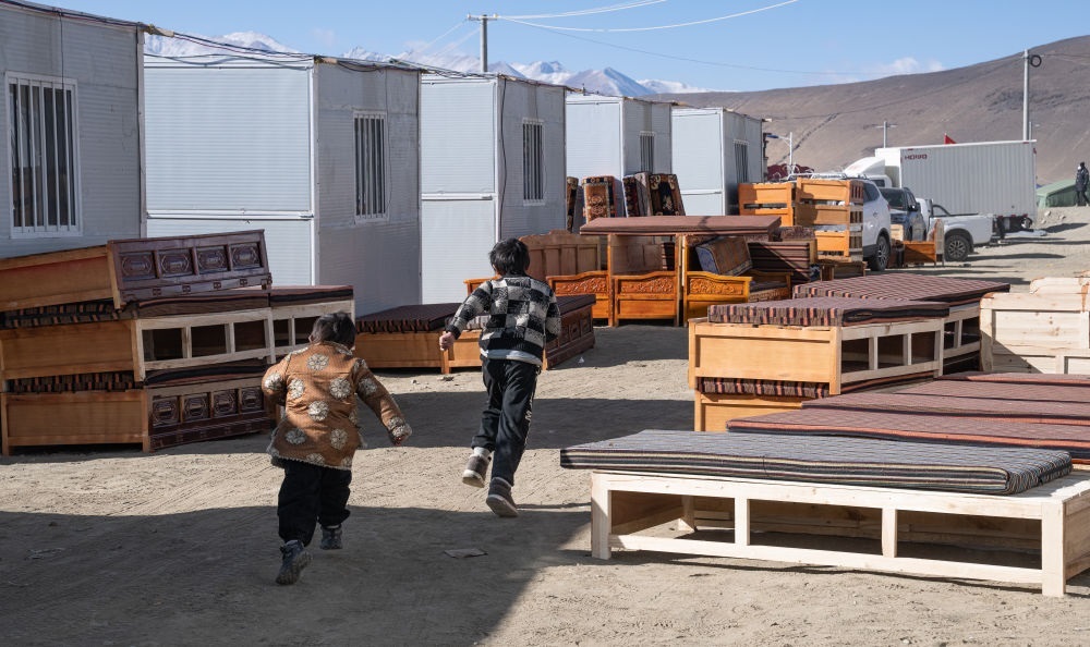 2025年1月13日，在定日縣嘎旦村，兩個(gè)孩子在剛運(yùn)來(lái)的兩排藏床間奔跑。新華社記者丁增尼達(dá) 攝