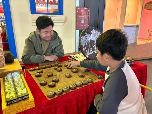 柯秋楓與市民下椰雕象棋。人民網(wǎng) 陳葉欣攝