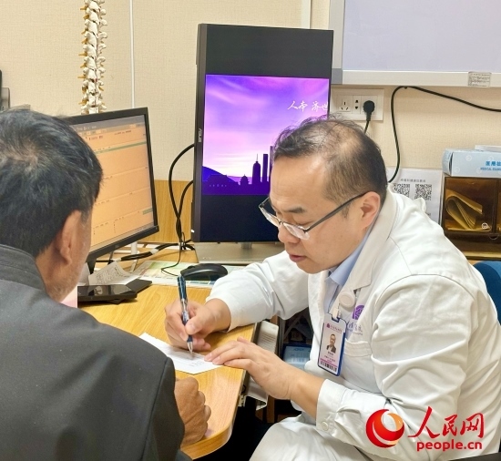 路桂軍接診時(shí)為患者寫下用藥提示。人民網(wǎng)記者 金慧慧攝