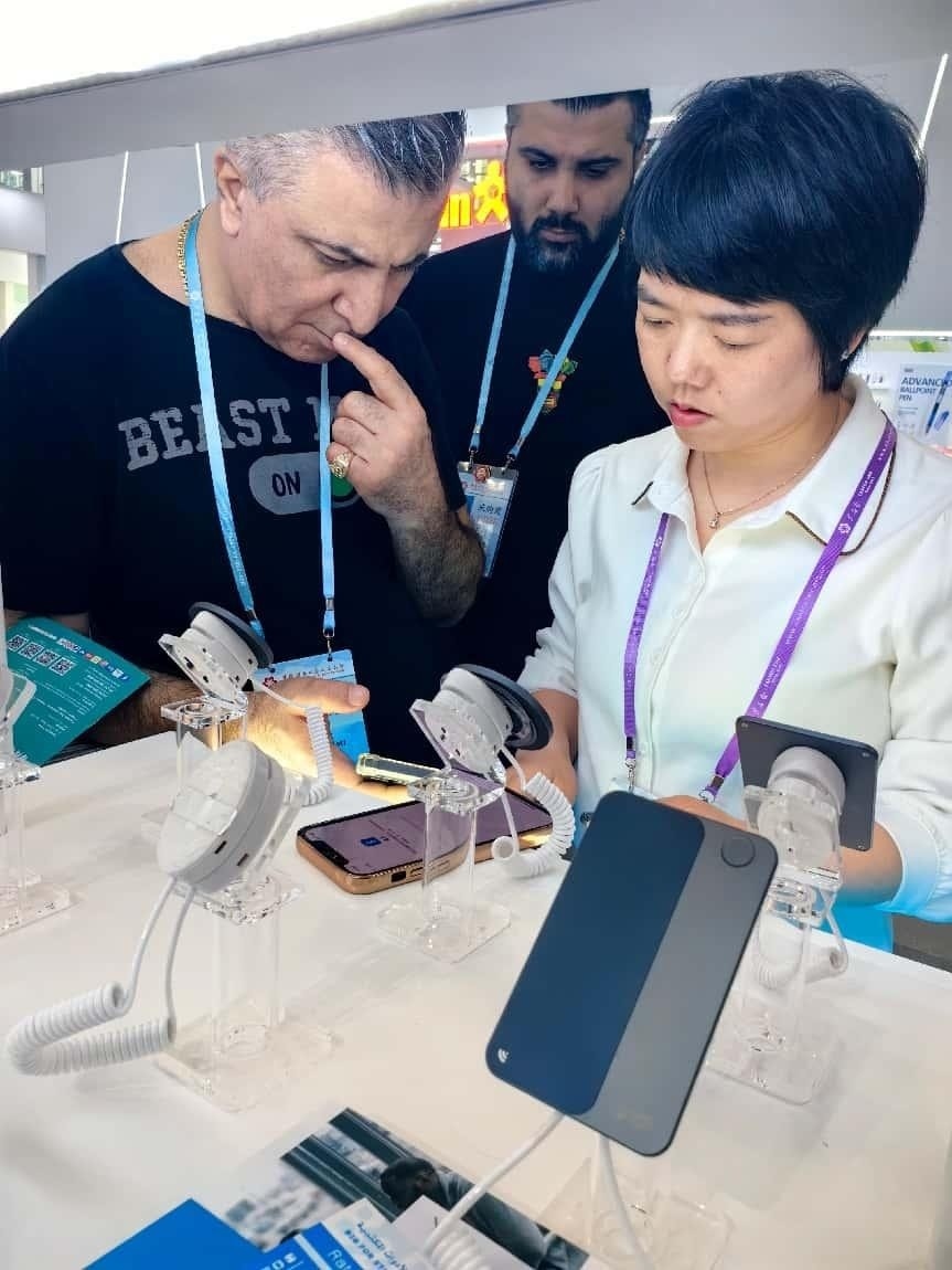 展臺工作人員向外商展示“AI TOP翻譯終端”。圖片來源：受訪者提供