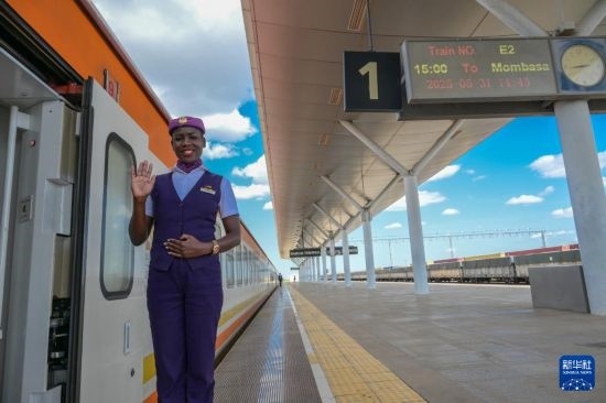 5月31日，在蒙內(nèi)鐵路內(nèi)羅畢站，一名乘務(wù)員在即將開往蒙巴薩的E2次列車旁等候乘客。新華社記者 楊光 攝