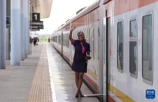 5月31日，在蒙內(nèi)鐵路內(nèi)羅畢站，一名乘務(wù)員在即將開往蒙巴薩的E2次列車旁等候乘客。新華社記者 李亞輝 攝